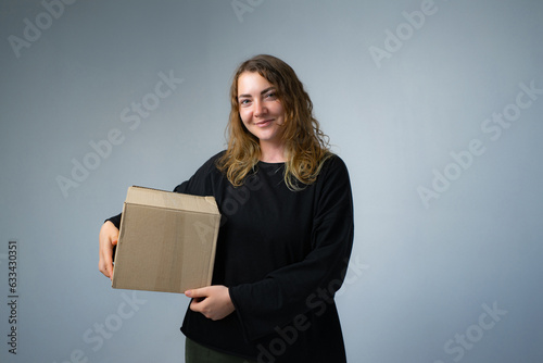 Happy woman moving in carrying cartons boxes with red paper house and key. Young girl arranging interior and unpacking at new apartment home. photo