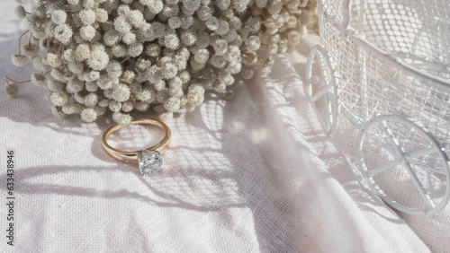 Close up of diamond ring with white flower, sunlight and shadow background. Love, valentine, relationship and wedding concept. Soft and selective focus.
