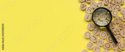 Concept of learning english, searching for word, and information. English alphabet letter and magnifying glass. Yellow background with copy space. photo