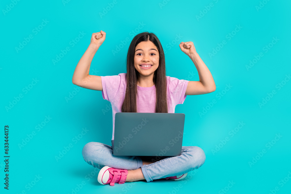 Full body photo cadre of small cute schoolgirl fists up enjoy playing computer games online victory isolated on cyan color background Full body photo cadre of small cute schoolgirl fists up enjoy playing computer games online victory isolated on cyan color background