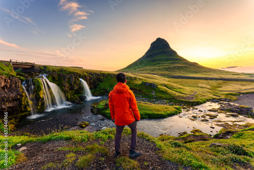 Traveler man standing with sunrise over Kirkjufell mountain in summer at Iceland