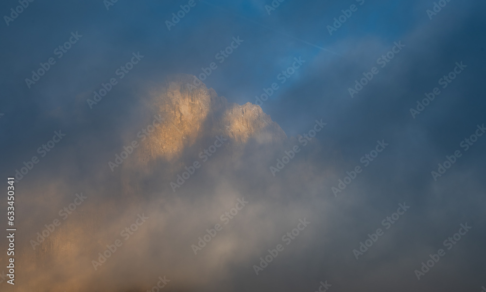 Foggy rocky mountain landscape at sunrise with blue sky.