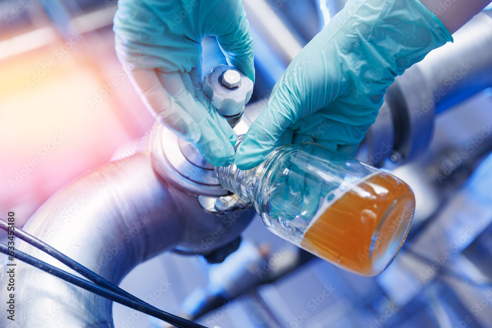 Laboratory assistant inspecting production beer, analysis drink in