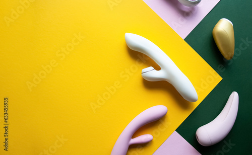 Collection of different types of sex toys on a pink, green and yellow background.