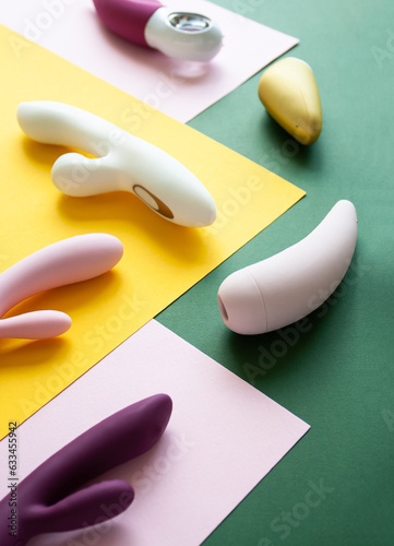 Collection of different types of sex toys on a pink, green and yellow background.