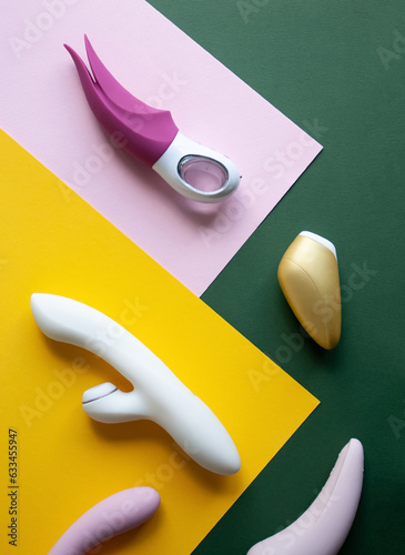 Collection of different types of sex toys on a pink, green and yellow background.