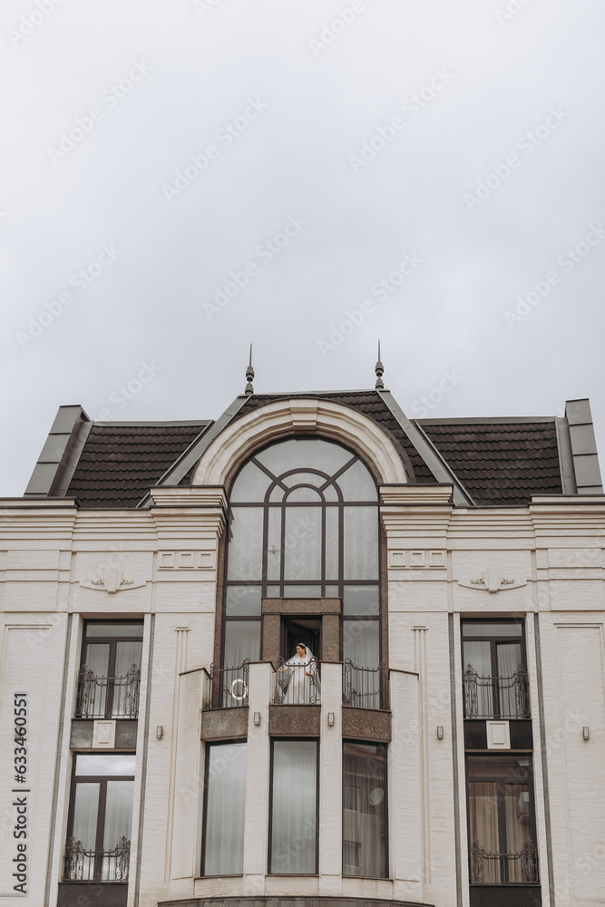 bride on the balcony of the hotel in a white robe with a veil, free space, vertical photo. On your wedding day