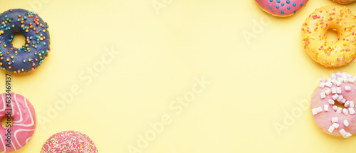 Different delicious donuts on light yellow background with space for text