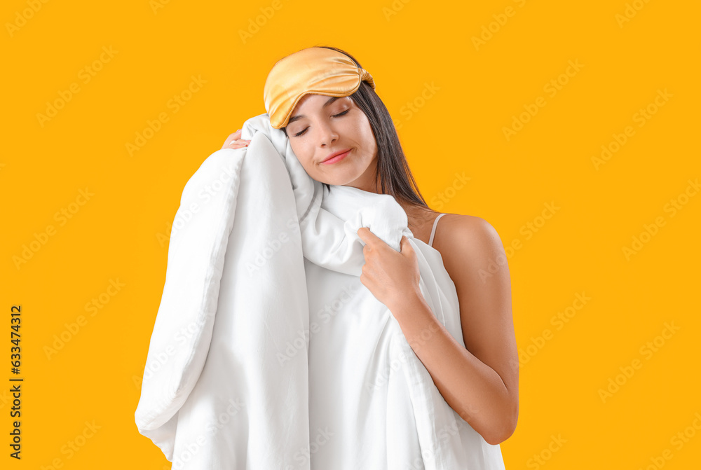 Young woman with sleeping mask and blanket on yellow background Young woman with sleeping mask and blanket on yellow background