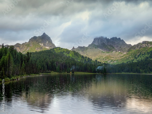 Amazing huge cloud above giant mountains. Raindrops on mountain lake. Wonderful droplets on lake water. Low clouds. Cloudy sky. Wonderful atmospheric ghostly highland landscape. West Sayans.