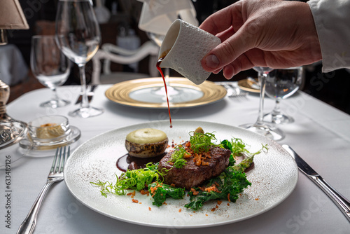Chef pouring sauce on meat dish