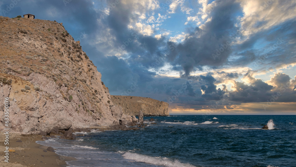 clouds clusters  in the sky on a deserted beach with magnificent cliffs and sea waves