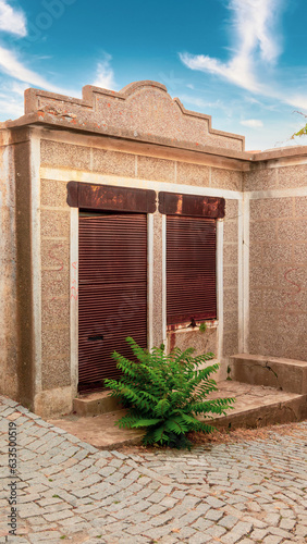 Frontal view of an abandoned old Greek grocery store in Tepekoy (Agridia) Gokceada, Turkey. shutters locked and rusted photo