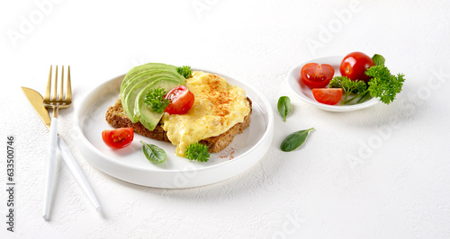 Omelette with tomato and avocado on bread on white plate