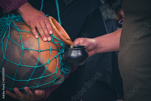 Saraguro culture of Ecuador handing out their traditional chicha, an ancestral drink, in a clay pot. photo