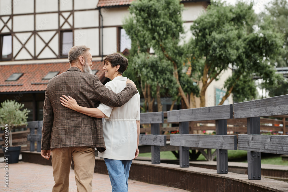 Obraz premium happy and elderly man and woman hugging and walking together outdoors, senior couple, romance