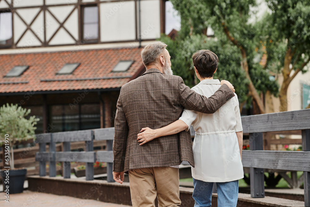 back view of elderly man and woman hugging and walking together outdoors, senior couple, romance back view of elderly man and woman hugging and walking together outdoors, senior couple, romance