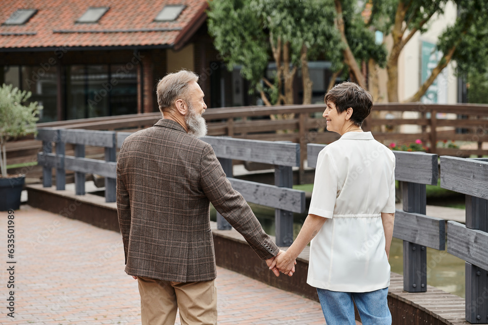 happy woman and bearded man holding hands, looking at each other, date, romance, elderly couple