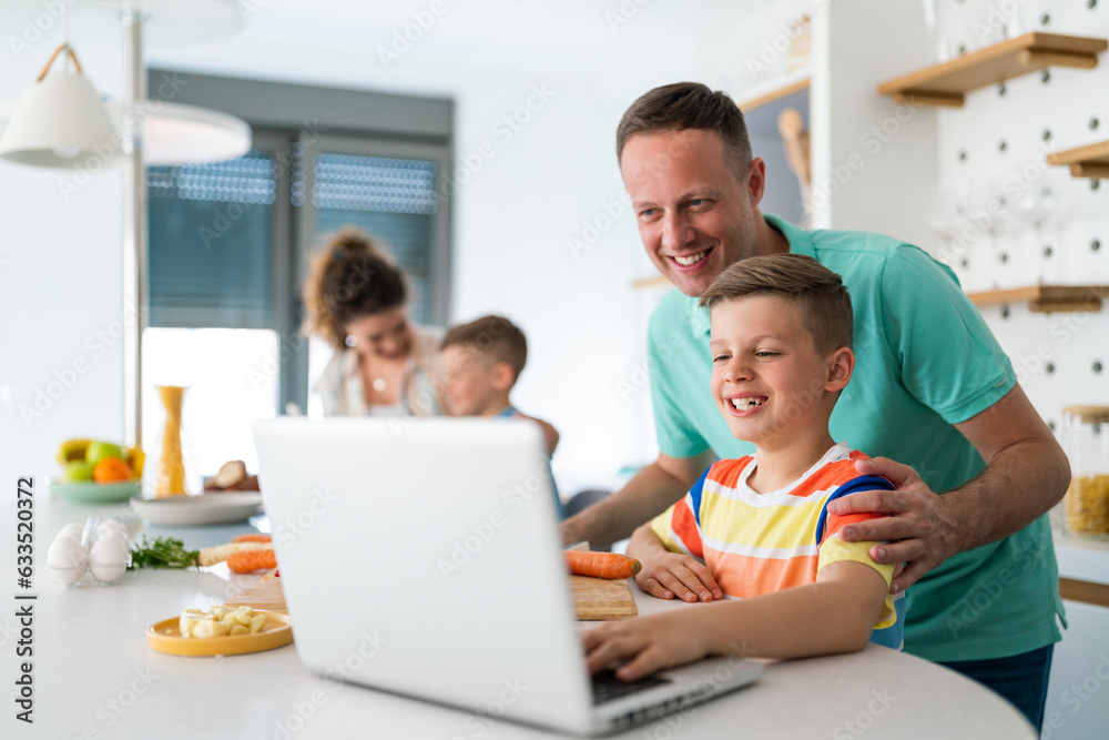 Portrait of jovial father and son exploring food recipes on laptop in the kitchen. Portrait of jovial father and son exploring food recipes on laptop in the kitchen.