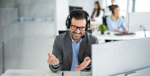 Dedicated male customer service representative communicating with customer trying to provide appropriate solutions for client issues at call center. photo