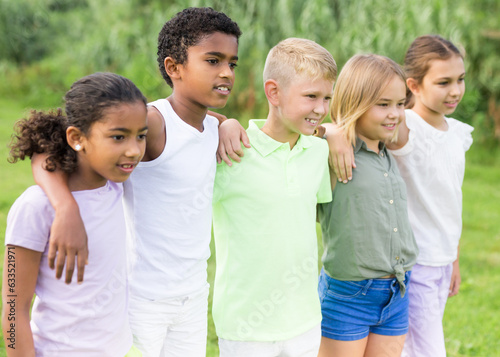 Portrait of happy children on green grass on bright sunny day