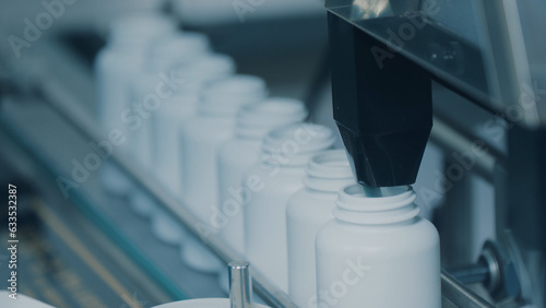 Photos 4K conveyor with moving empty white plastic tubes on the production line and filling with capsules