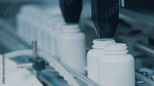 4K conveyor with moving empty white plastic tubes on the production line and filling with capsules. Automatic machine in the factory. Modern High-Tech Pharmacology Factory. Close Up, DOF