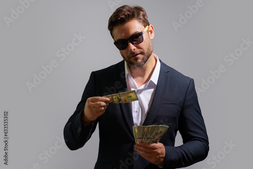 Business man hold money on gray studio isolated background. Rich man in suit with money dollar bills. Successful businessman with dollar banknotes. Rich millionaire in suit holding money.