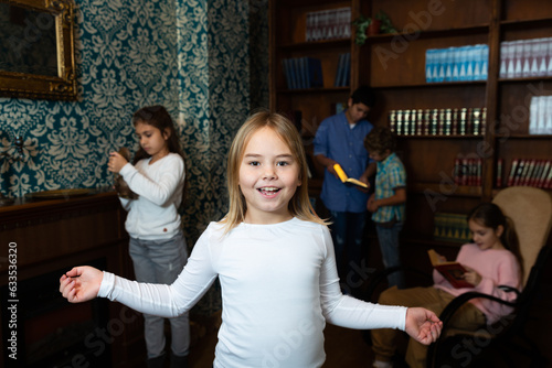 Portrait of cheerful cute preteen girl having fun in quest room with her friends