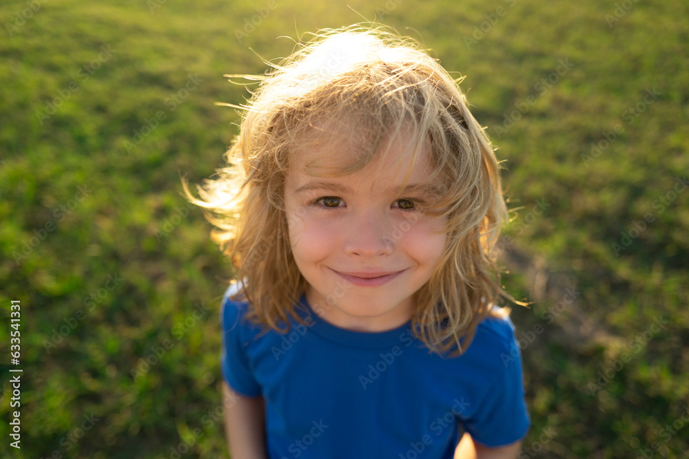 Portrait of kid boy in nature, park or outdoors. Close up face of happy child playing outdoors in summer park. Portrait of kid boy in nature, park or outdoors. Close up face of happy child playing outdoors in summer park.