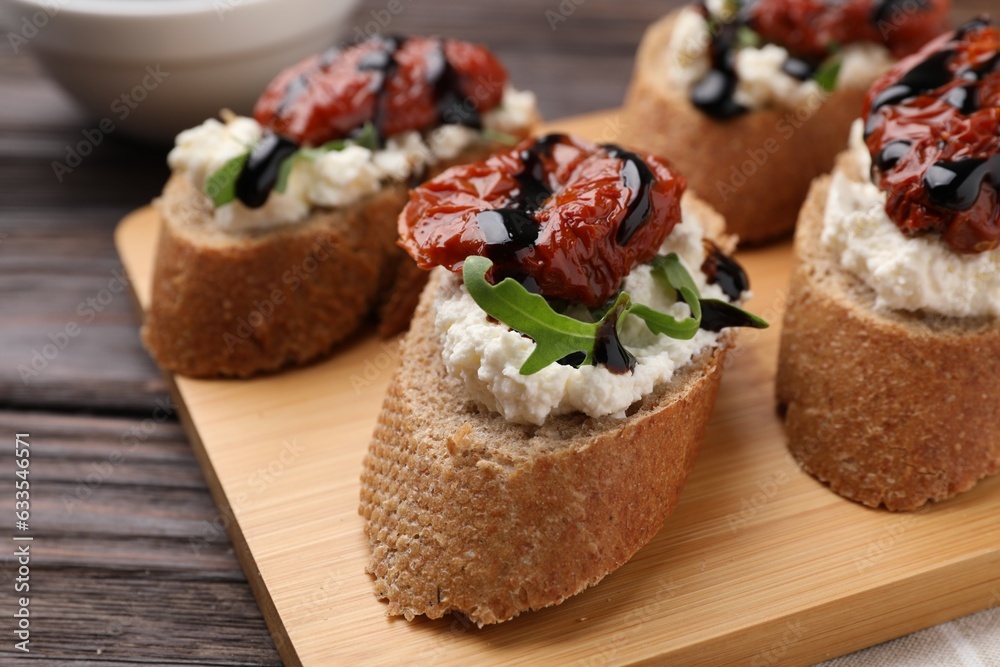 Delicious bruschettas with sun-dried tomatoes, cream cheese and balsamic vinegar on wooden table, closeup Delicious bruschettas with sun-dried tomatoes, cream cheese and balsamic vinegar on wooden table, closeup
