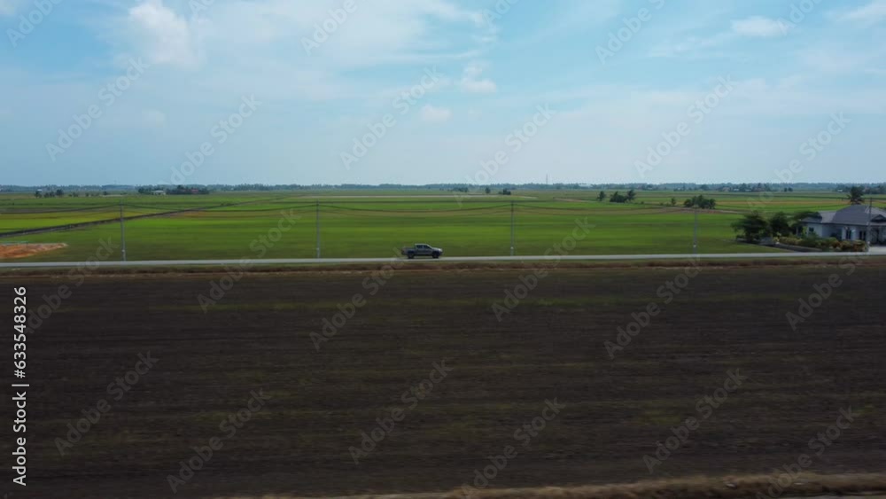 Pickup truck sideways follow and reveal drone shot surrounded with green paddy fields. Pickup truck sideways follow and reveal drone shot surrounded with green paddy fields.