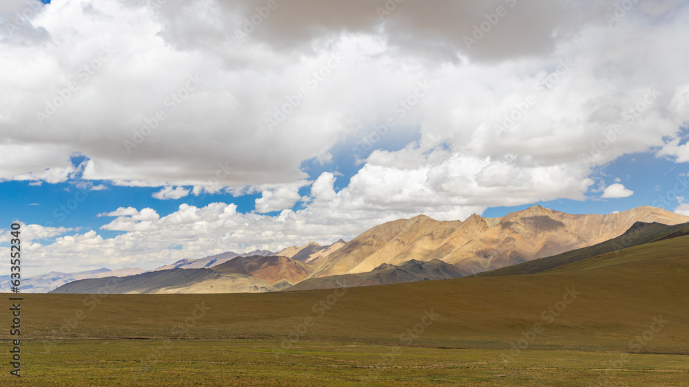 An open landscape at the higher reaches of Ladakh with brown pastures and clouds