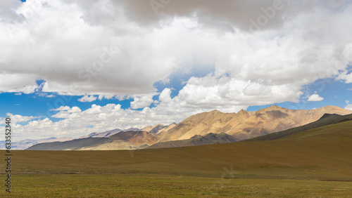 An open landscape at the higher reaches of Ladakh with brown pastures and clouds