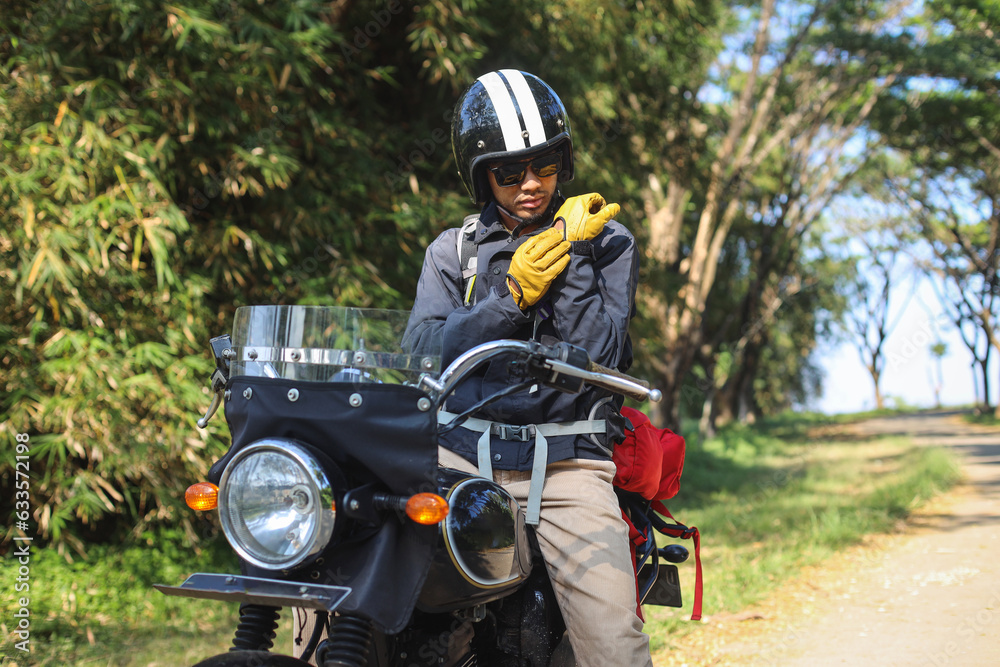 Young Asian man in a motorcycle with helmet is wearing gloves. Safety riding concept. Young Asian man in a motorcycle with helmet is wearing gloves. Safety riding concept.