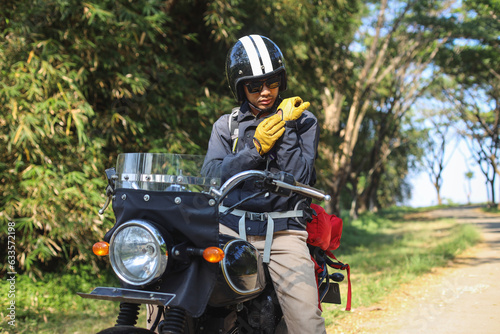 Young Asian man in a motorcycle with helmet is wearing gloves. Safety riding concept. 