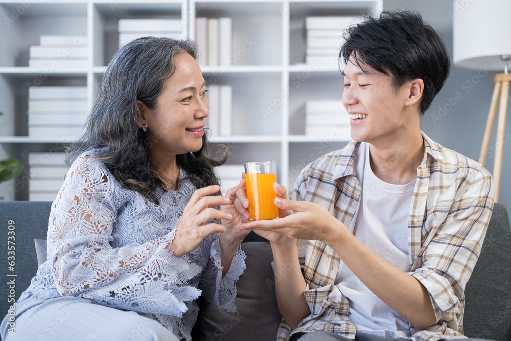 Loving elderly mother receiving.orange juice from adult son spending time together at home. Family, love and bonding concept Loving elderly mother receiving.orange juice from adult son spending time together at home. Family, love and bonding concept