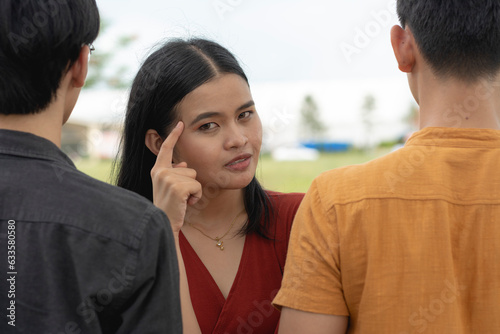 A cheerful young woman in the middle of two anonymous men facing the opposite way. Choosing the right partner. Advising to select the right one with your brain. Dating concept.