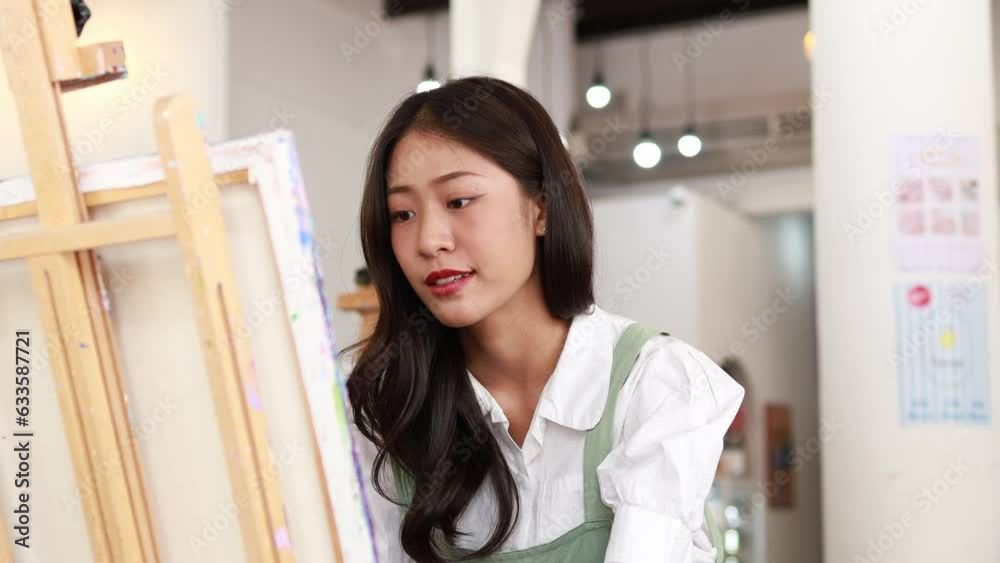 Asian woman painting on canvas, she is an artist who creates watercolor painting, art painting. Concept artist design drawing art on canvas paper. Asian woman painting on canvas, she is an artist who creates watercolor painting, art painting. Concept artist design drawing art on canvas paper.
