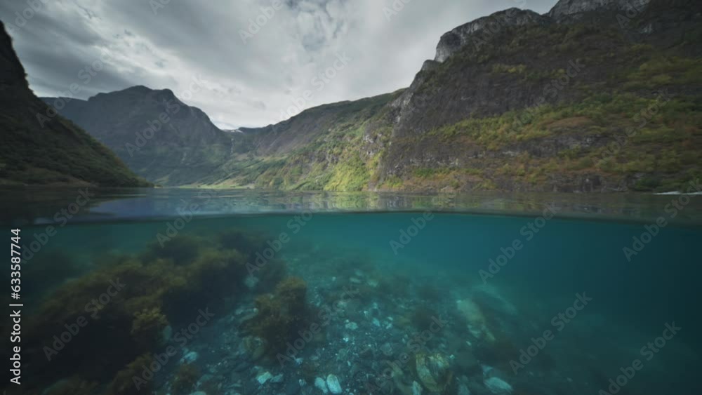 An over-under water shot. Discover the breathtaking fjord landscape with rocky shores and swaying underwater weeds. An over-under water shot. Discover the breathtaking fjord landscape with rocky shores and swaying underwater weeds.