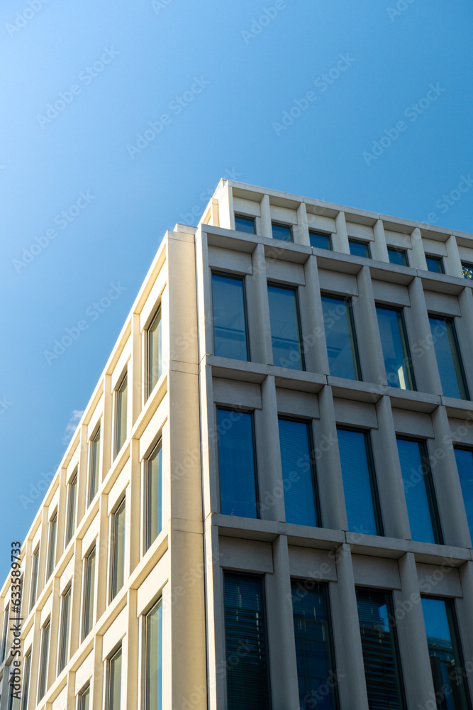 Modern office building exterior with glass facade on clear sky background. Transparent glass wall of office building with yellow decoration. Element of facade of modern European building Commercial