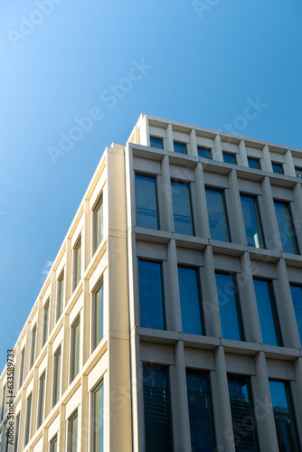 Modern office building exterior with glass facade on clear sky background. Transparent glass wall of office building with yellow decoration. Element of facade of modern European building Commercial