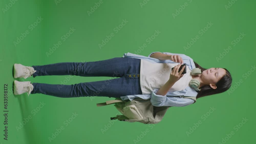 Full Body Of Asian Teen Girl Student With A Backpack Using A Smartphone And Pointing To Side While Standing In The Green Screen Background Studio
Full Body Of Asian Teen Girl Student With A Backpack Using A Smartphone And Pointing To Side While Standing In The Green Screen Background Studio