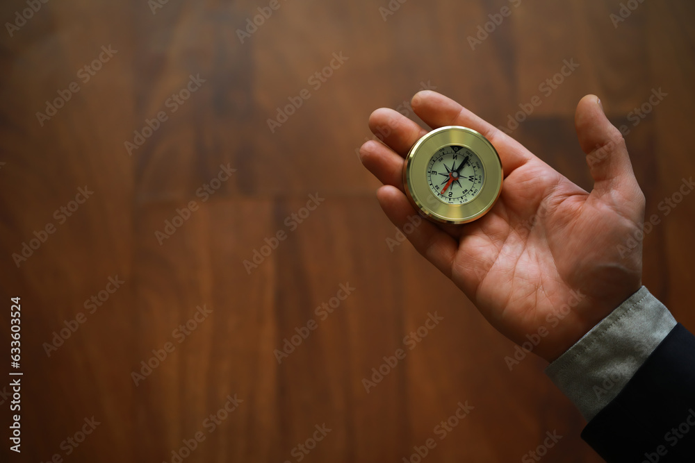 man in suit holding golden compass on gray background man in suit holding golden compass on gray background