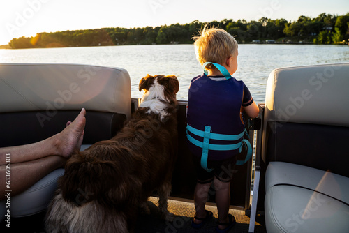 Blonde Toddler Boy Looking at Water on Boat with Family Dog photo