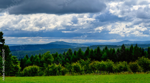 Clouds over the mountains. rural areas. Panorama of hills covered with trees with green meadows. Bieszczady, Poland