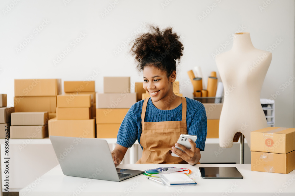 Startup small business SME, Entrepreneur owner African woman using smartphone or tablet taking receive and checking online purchase shopping order to preparing pack product box. in office. Startup small business SME, Entrepreneur owner African woman using smartphone or tablet taking receive and checking online purchase shopping order to preparing pack product box. in office.
