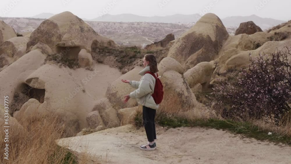 Teenage girl juggling rock while standing on top of mountain. Handheld shot of female child hiking in rocky landscape. She is carrying backpack while enjoying nature.