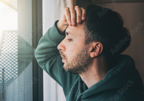 Tired man looks at window. Sad Middle-age person in life crisis or problems. Work depression or business bankruptcy concept.