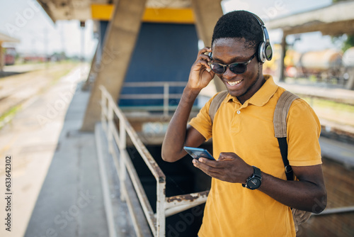 Young man with headphones and mobile phone on the train station